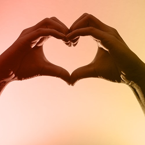 Hands forming a heart silhouette against gradient background.